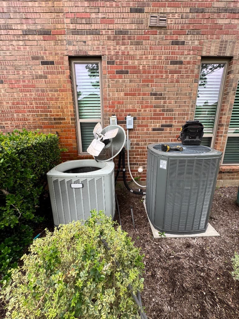 Two residential AC condenser units outside a North Texas brick home — covered by the Access Comfort Care Agreement